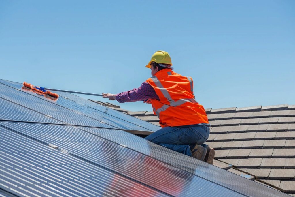 A man in an orange vest is working on solar panels.