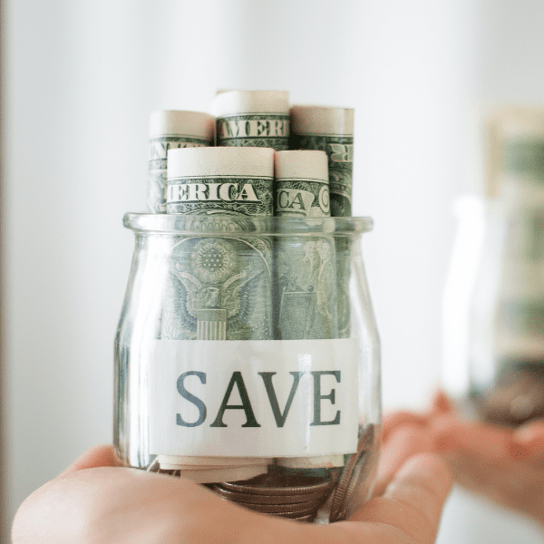 A person holding a jar of money with the word save on it.