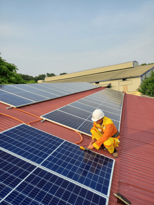 A man in yellow work clothes standing on the roof of a building.