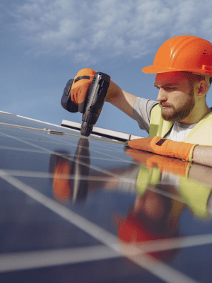 A man in an orange helmet is working on solar panels.